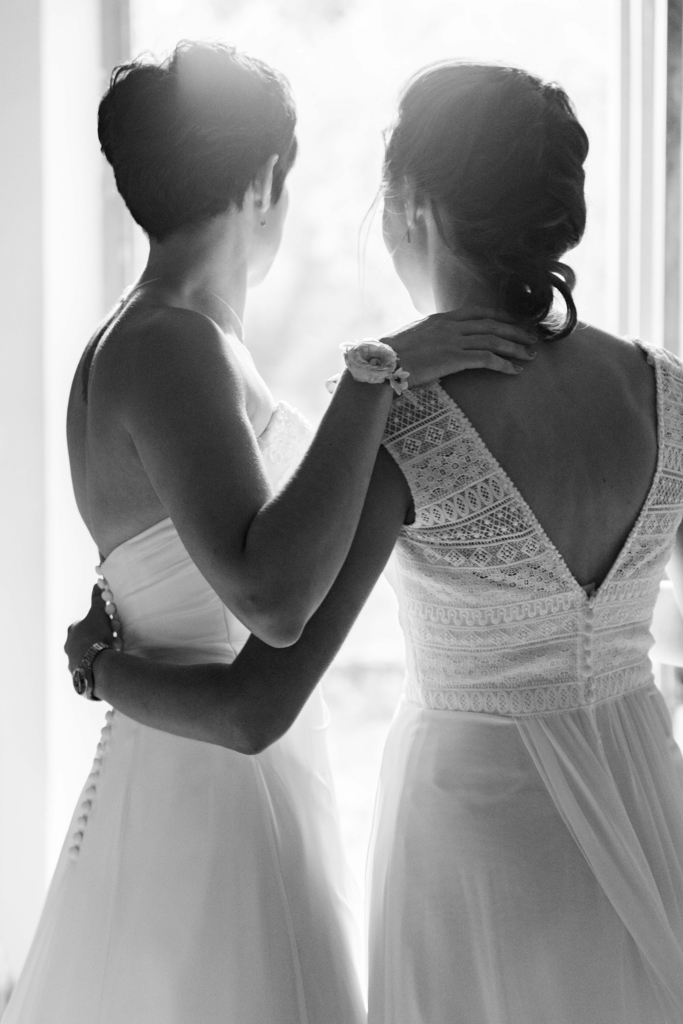 Accueil - Patrick PIERRE Photographe Photographie du mariage de deux jeunes femmes regardant la lumière provenant d'une porte ouverte. Cette lumière symbolise l'amour et la nouvelle vie qui les attend. Photographe Patrick PIERRE
